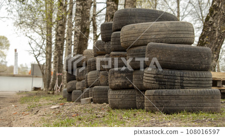 folded old car tires lie on the ground near the road 108016597