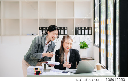 Businesswomen work and discuss their business plans. A Human employee explains and shows her colleague the results paper in office.. 108016660