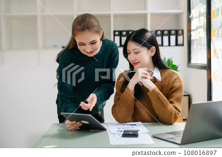 Two business workers talking on the smartphone, tablet and using laptop at the office... 108016897