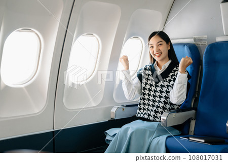 Young Asian executive excels in first class, multitasking with digital tablet, laptop and smartphone. Travel in style, work with grace. in morning light. 108017031