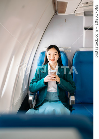 Attractive Asian female passenger of airplane sitting in comfortable seat while working laptop and tablet with mock up area using wireless connection. Travel in style, work with grace.. 108017069