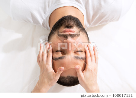 Facial massage for young man for reducing puffiness by professional massage therapist in beauty clinic Facial massage for young man for reducing puffiness by professional massage therapist in beauty clinic 108017131