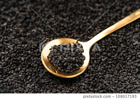 Black cumin seeds on golden spoon macro photography Black cumin seeds on golden spoon macro photography 108017193