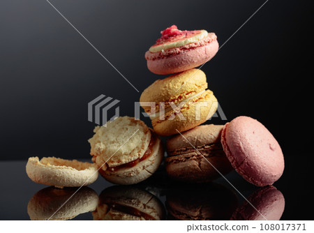 Delicious colorful macaroons on a black reflective background. Delicious colorful macaroons on a black reflective background. 108017371