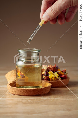 Dropping essential oil or herbal tincture into a glass bottle. 108017409