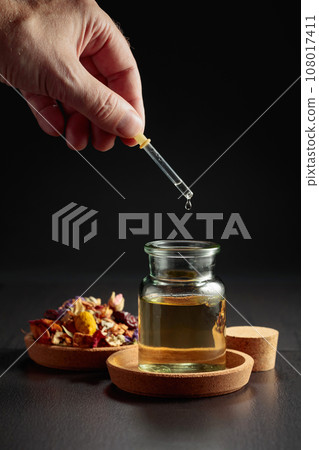 Dropping essential oil or herbal tincture into a small bottle. Dropping essential oil or herbal tincture into a small bottle. 108017411