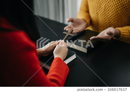 Two people reading and study bible in home and pray together.Studying the Word Of God With Friends.. 108017637