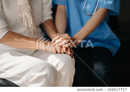 Close up view of old woman leaning on nurse while siting. 108017757