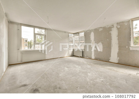 an empty room with white walls and dry plaster all over the floor, there is a window in the wall an empty room with white walls and dry plaster all over the floor, there is a window in the wall 108017792