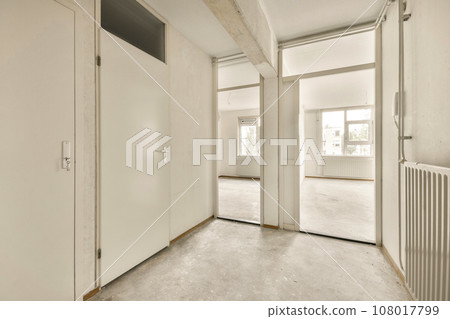 an empty room with white walls and floorboards on the wall, there is a rad door in the corner an empty room with white walls and floorboards on the wall, there is a rad door in the corner 108017799
