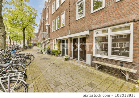 bikes parked on the side of a street in front of a brick building with white windows and doors that are open bikes parked on the side of a street in front of a brick building with white windows and doors that are open 108018935