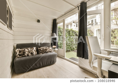 a living room with wood flooring and white walls, an open window to the garden is visible on the right side 108018946
