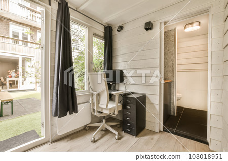 a room with a desk, chair and computer on the floor in front of an open door that leads to a patio 108018951