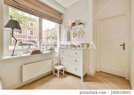 a room with wooden flooring and white cupboards in front of the window, there is a lamp on it a room with wooden flooring and white cupboards in front of the window, there is a lamp on it 108019005