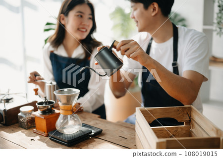 Cute couple, male and female barista working in coffee shop Barista working at cafe Alternative ways of brewing coffee.    . Cute couple, male and female barista working in coffee shop Barista working at cafe Alternative ways of brewing coffee.    . 108019015