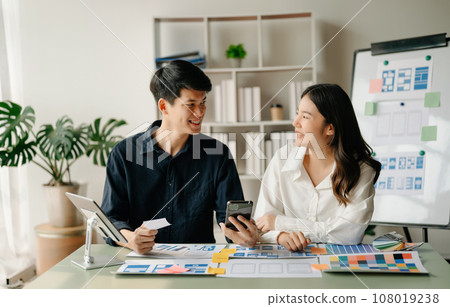 UX developer and ui designer brainstorming about mobile app interface wireframe design with customer breif and color code at office.. UX developer and ui designer brainstorming about mobile app interface wireframe design with customer breif and color code at office.. 108019238