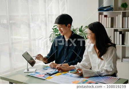UX developer and ui designer brainstorming about mobile app interface wireframe design with customer breif and color code at office.. UX developer and ui designer brainstorming about mobile app interface wireframe design with customer breif and color code at office.. 108019239