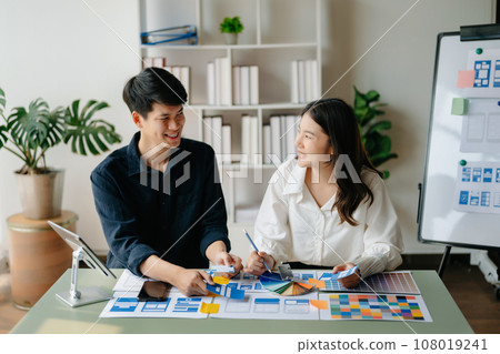 UX developer and ui designer brainstorming about mobile app interface wireframe design with customer breif and color code at office.. UX developer and ui designer brainstorming about mobile app interface wireframe design with customer breif and color code at office.. 108019241