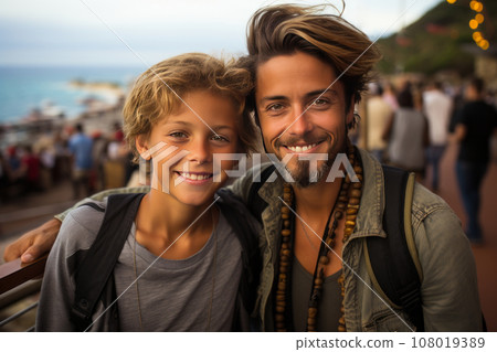 Young boy and his older brother against the backdrop of a city fair or amusement park on the seacoast. Cheerful, smiling brothers relaxing and enjoying their time. Leisure and entertainment. 108019389