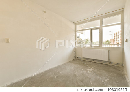 an empty room with white walls and no one person standing in the corner looking out at the view from the window an empty room with white walls and no one person standing in the corner looking out at the view from the window 108019815