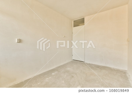 an empty room with white walls and no one door on the other wall there is a hole in the wall 108019849