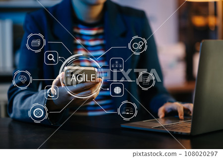 Agile development methodology concept. Business hand using laptop computer and tablet with virtual screen Agile icon on modern office digital technology concept.. Agile development methodology concept. Business hand using laptop computer and tablet with virtual screen Agile icon on modern office digital technology concept.. 108020297