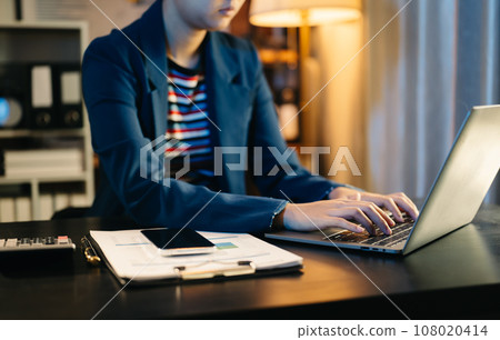 Confident businessman working on laptop,tablet and smartphone at her workplace neon light in dark time. at office. Confident businessman working on laptop,tablet and smartphone at her workplace neon light in dark time. at office. 108020414