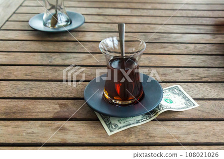 Money left to the waiter in a cafe as a tip. Dollar under a cup for a tip to the waiter 108021026