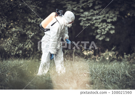 A worker sprays pesticides on trees outdoors. Tree pest control 108021560