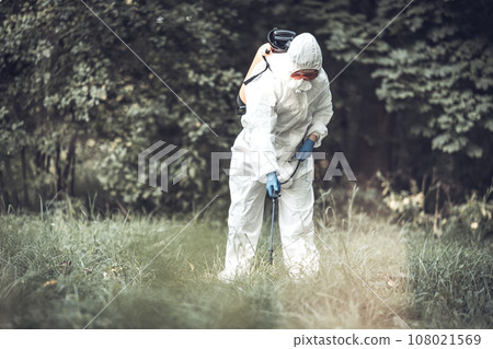 A worker sprays pesticides on trees outdoors. Tree pest control 108021569