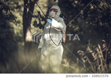 A worker sprays pesticides on trees outdoors. Tree pest control 108021570