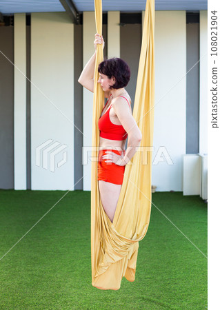 Woman practicing on aerial sheets, aerial gymnastics class outdoors 108021904