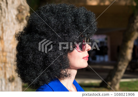 Portrait of a woman in profile. Side view of a girl with a lush hairstyle of curly black hair 108021906