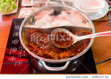 spoon with spicy broth over wok during cooking spoon with spicy broth over wok during cooking 108022138