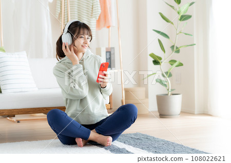 在客廳裡聽音樂的年輕女人 108022621