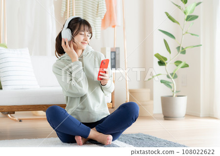 在客廳裡聽音樂的年輕女人 108022622