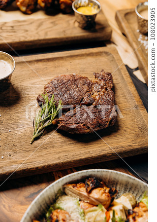 Fresh juicy delicious beef steak on wooden background in restaurant. Meat dish with spices and herbs 108023905