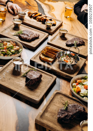 Tasty dishes in restaurant with beef steak, salad and barbecue chicken wings. Food menu concept 108023907