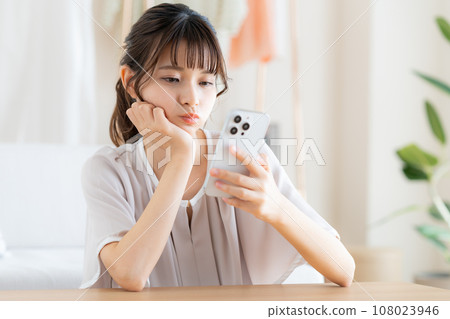 年輕女子在客廳看智慧型手機 108023946