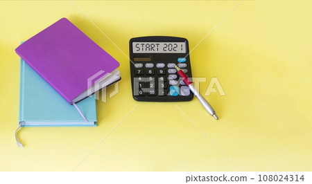 The calculator has the text Start 2021, next to multi-colored notebooks  108024314