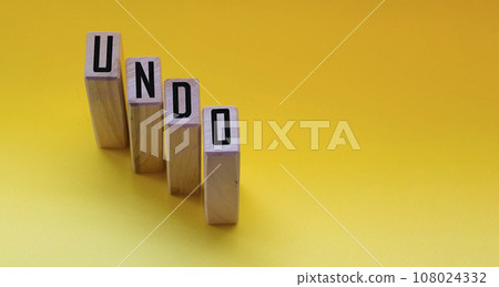 Undo word on wooden cubes with letters on yellow background. The concept Undo word on wooden cubes with letters on yellow background. The concept 108024332