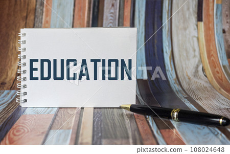The word EDUCATION is written on a notepad and on a striped background. The word EDUCATION is written on a notepad and on a striped background. 108024648