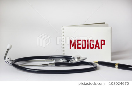 Medigap word on notepad, stethoscope and white background Medigap word on notepad, stethoscope and white background 108024670