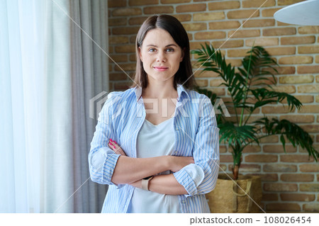 Portrait of smiling confident young woman with crossed arms 108026454