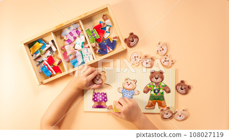 Little girl hands playing with eco game. Game for visually displaying emotions, ssensory processing disorder, activities Montessori. Little girl hands playing with eco game. Game for visually displaying emotions, ssensory processing disorder, activities Montessori. 108027119