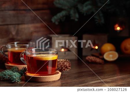 Tea with lemon and small Christmas lanterns on a wooden table. 108027126