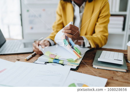 financial, Planning, Marketing and Accounting, portrait of african american employee checking financial statements using documents and calculators at work. financial, Planning, Marketing and Accounting, portrait of african american employee checking financial statements using documents and calculators at work. 108028656