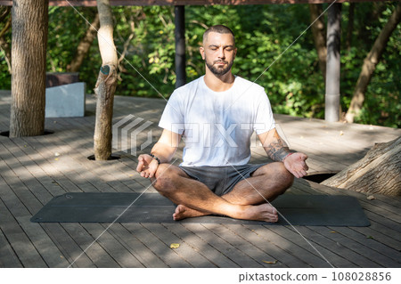 Handsome yogi man practicing yoga meditation outdoors sitting in lotus position. Handsome yogi man practicing yoga meditation outdoors sitting in lotus position. 108028856