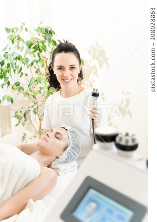 Radio frequency lifting in modern cosmetology. Cosmetic doctor and patient in cosmetology clinic. Vertical photography. 108028863