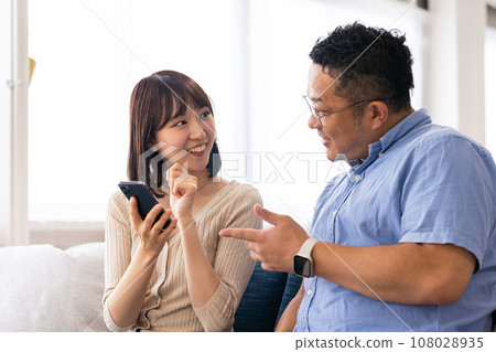 A man and a woman using smartphones in the living room A man and a woman using smartphones in the living room 108028935